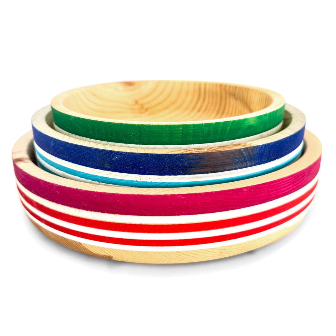 Stack of three hand-turned wooden bowls in red, blue, and green with natural wood interiors.