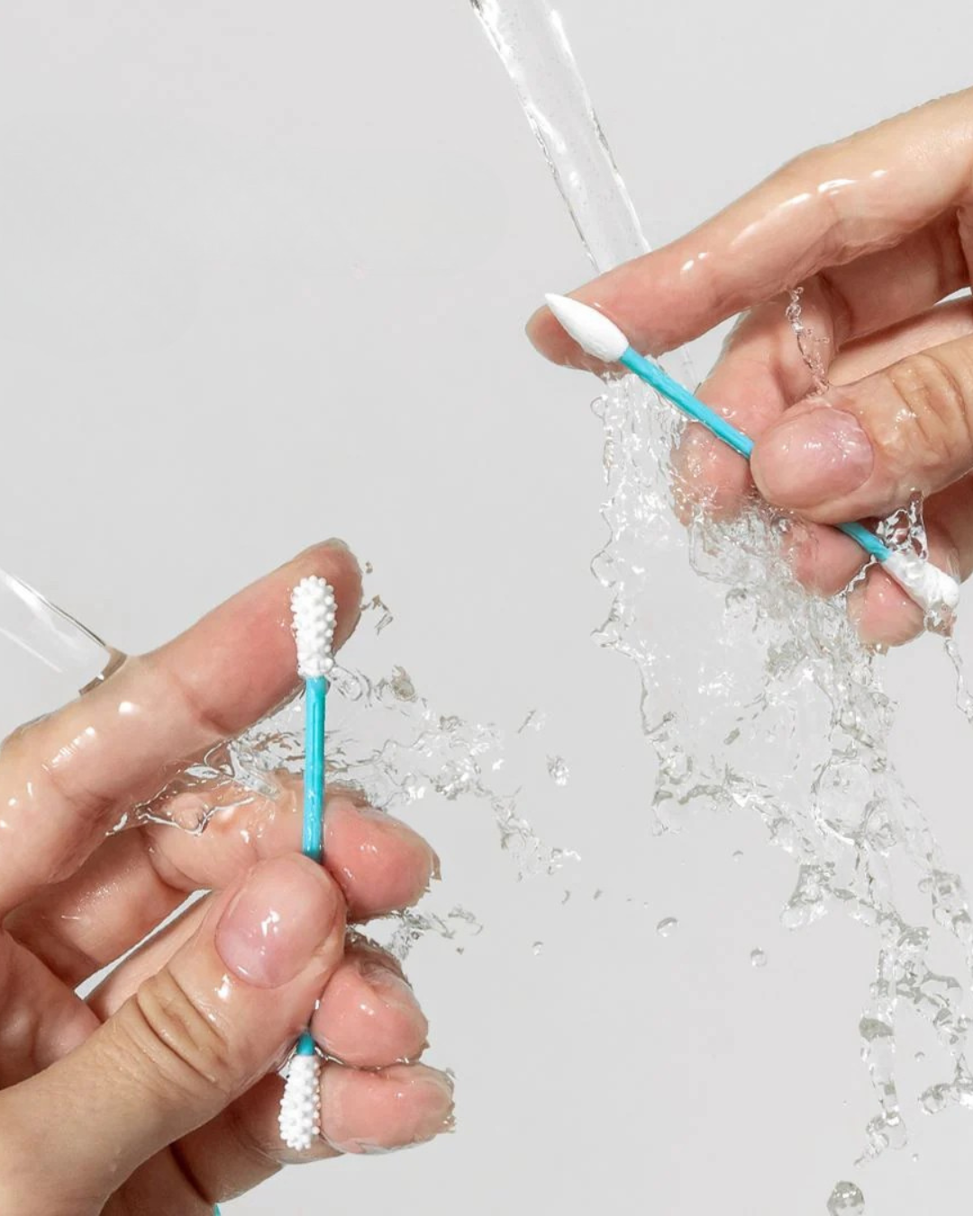 Zwei Hände halten wiederverwendbare Ohrenstäbchen aus PTE unters Wasser
