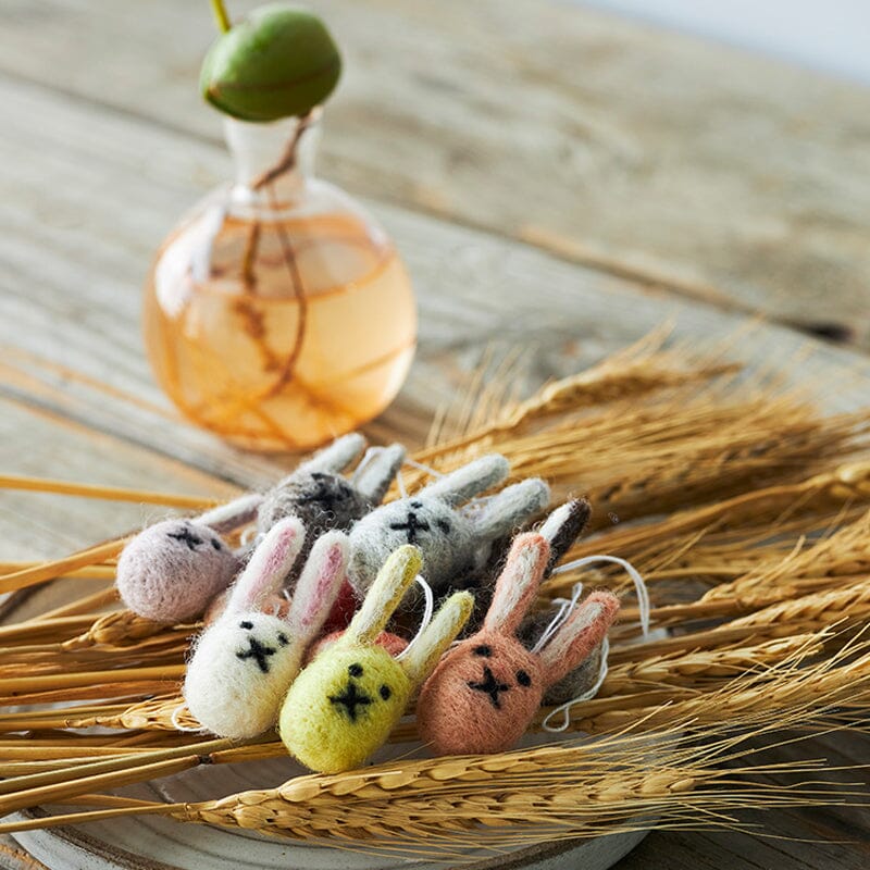 Osterhasen-Anhänger aus Wollfilz von Aveva. Anhänger liegen auf Stroh